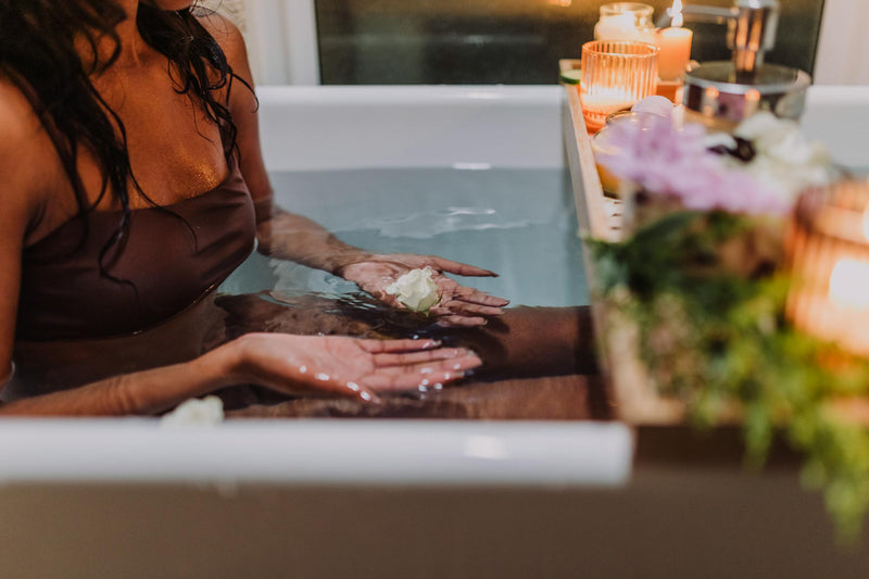 Woman relaxing in spa bath with flowers and candles